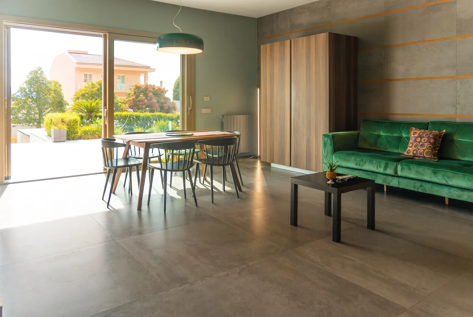 Soggiorno con divano verde e zona pranzo a Villa Bizzarria